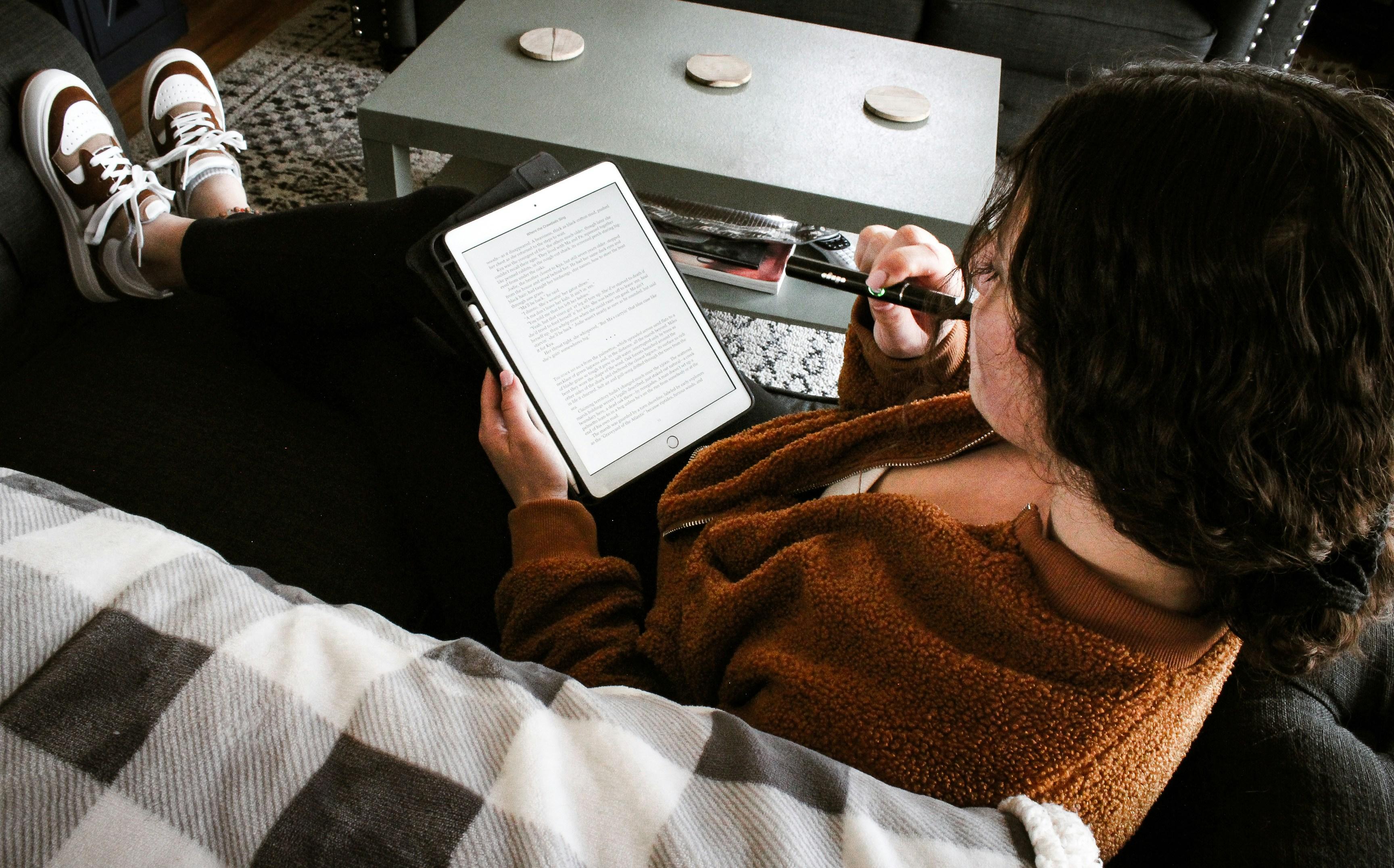 woman vaping and reading something on her tablet