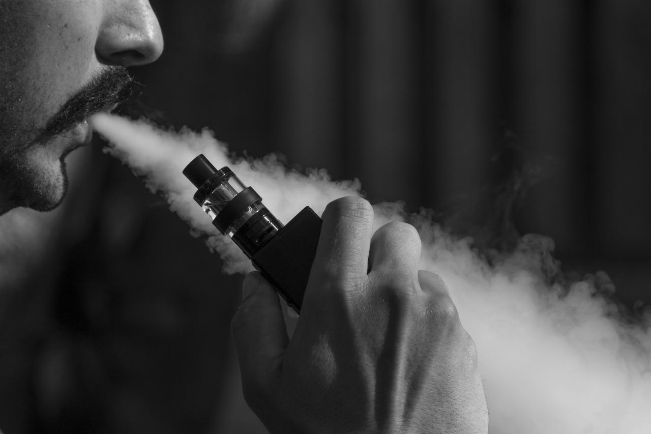 black and white picture of man exhaling vape